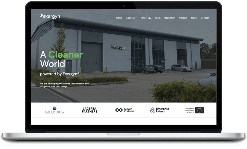The image shows a laptop displaying a website for 'Exergyn', a company promoting a cleaner world through their technology. The website features a building exterior.
